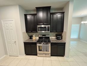 Houston house for rent - A kitchen with black cabinets and a granite countertop.