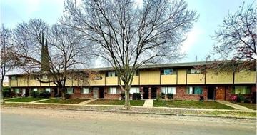 Fresno apartment for rent - A long building with a tree in front of it.