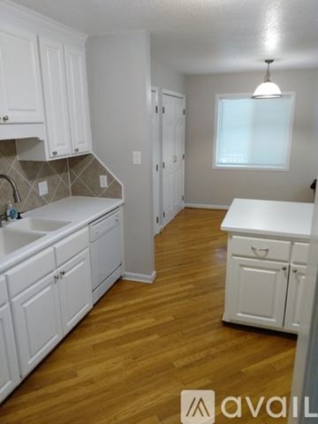 Durham house for rent - A kitchen with white cabinets and wooden floors.
