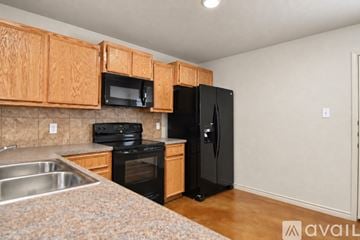 Copperas Cove apartment for rent - A kitchen with wooden cabinets and black appliances.