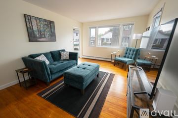 Providence house for rent - A living room with a green couch and a black and white striped rug.