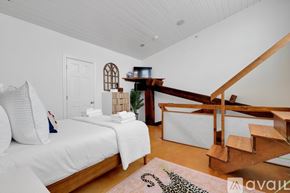 Savannah apartment for rent - A bedroom with a white bed and a wooden staircase.