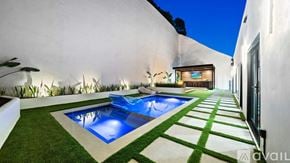 , Beverly Hills house for rent - A modern outdoor pool area with a green lawn and a white wall.