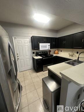 Houston townhouse for rent - A kitchen with black cabinets and a white fridge.