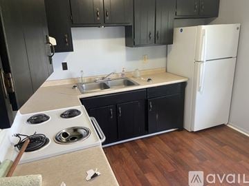 Oak Hill apartment for rent - A kitchen with black cabinets and a white refrigerator.