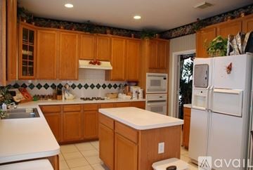 Houston house for rent - A kitchen with wooden cabinets and a white fridge.