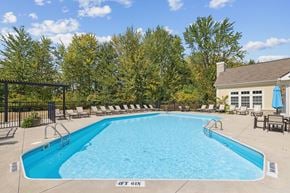 Westerville apartment for rent - A swimming pool surrounded by a fence and a building in the background.