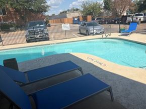 Fort Worth apartment for rent - A pool with blue loungers and a sign that says "POOL" on the side.
