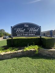 Fort Worth apartment for rent - A sign for West Wind Apartments is displayed in front of a building.