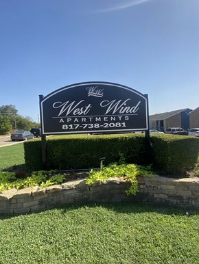 Fort Worth apartment for rent - A sign for West Wind Apartments is displayed in front of a building.