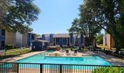 Fort Worth apartment for rent - A swimming pool surrounded by a black fence and trees.