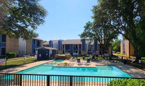 Fort Worth apartment for rent - A swimming pool surrounded by a black fence and trees.