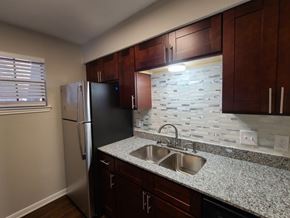 Sherman apartment for rent - A kitchen with a black refrigerator and brown cabinets.