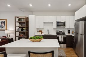 Woodbridge apartment for rent - A modern kitchen with a white table and a bowl of green apples on it.