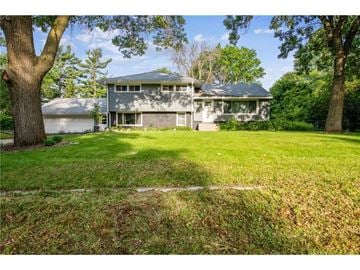Burnsville house for rent - A house with a grey roof and a white garage door is surrounded by trees.