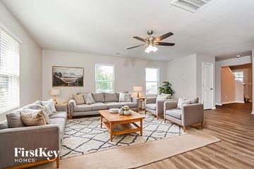 Kernersville house for rent - A spacious living room with a large grey sofa, a wooden coffee table, and a painting on the wall.