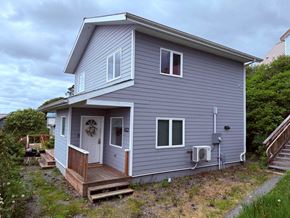 Sitka house for rent - A house with a grey siding and a white door is shown.