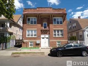 Bridgeport townhouse for rent - A black car is parked in front of a two-story brick house.