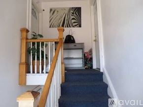 Bridgeport townhouse for rent - A staircase with a wooden railing and a blue carpeted runner.