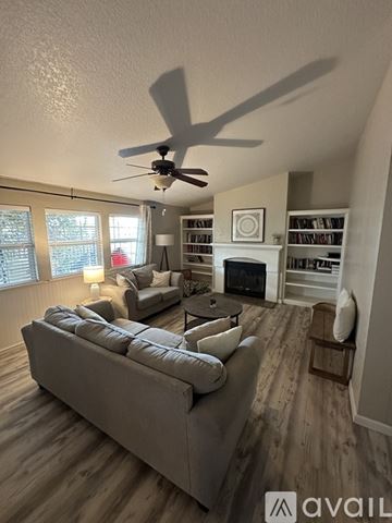 Peoria house for rent - A living room with a grey sofa and a ceiling fan.