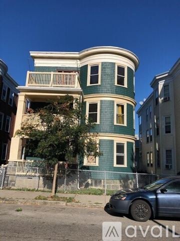 Boston apartment for rent - A blue car is parked in front of a green and white building.