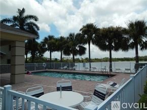 Bradenton townhouse for rent - A pool surrounded by palm trees and deck chairs.