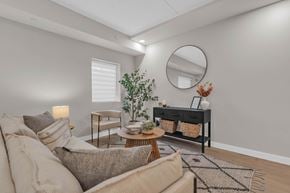 Winnipeg apartment for rent - A living room with a beige sofa, a round mirror, and a wooden coffee table.