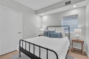 Winnipeg apartment for rent - A bedroom with a black metal bed frame and a white bedspread.