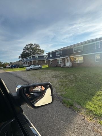 Springville apartment for rent - A car is parked in front of a building with a grassy area in the foreground.