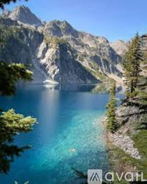 Snoqualmie Pass house for rent - A boat is sailing in a lake surrounded by mountains.