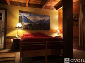 Snoqualmie Pass house for rent - A bedroom with a bed, two lamps, and a mountain painting on the wall.