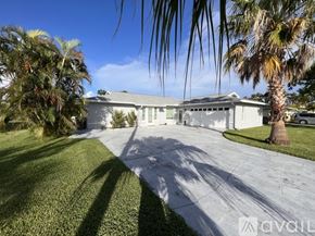 Cape Coral house for rent - A white house with a driveway and palm trees in front.