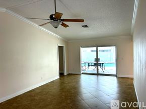 Cape Coral house for rent - A person is sitting on a chair in a patio area with a pool.