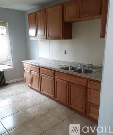 Brockton house for rent - A kitchen with brown cabinets and a white countertop.