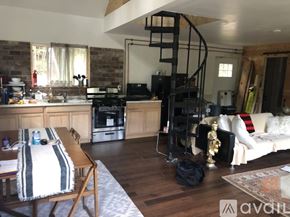 Middlesex house for rent - A living room with a spiral staircase and a kitchen area.