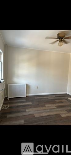 Scranton house for rent - A room with a ceiling fan and wooden flooring.