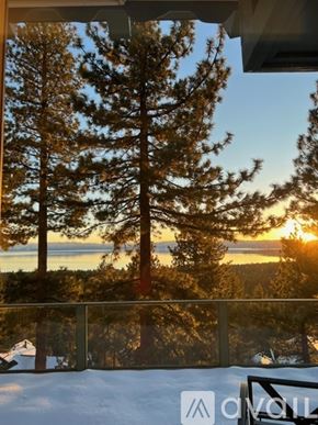 Incline Village condo for rent - A view of a snowy landscape with trees and a sunset.
