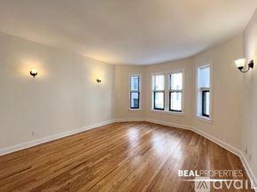 Chicago apartment for rent - A spacious room with wooden floors and three windows.