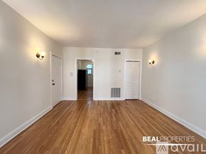 Chicago apartment for rent - A room with wooden floors and white walls, with a door at the end of the hallway.