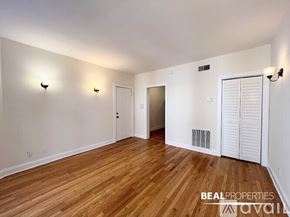 Chicago apartment for rent - A room with wooden flooring and white walls, with a door on the right and a window on the left.