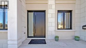 Toronto (St. Andrew-Windfields) house for rent - A modern house entrance with a glass door and two potted plants on either side.