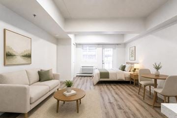 Saskatoon apartment for rent - A living room with a couch, a coffee table, a bed, and a painting on the wall.