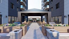 Saskatoon apartment for rent - A modern building entrance with a walkway and flower beds on either side.