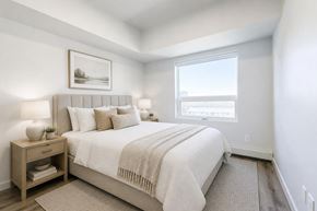 Saskatoon apartment for rent - A bedroom with a large bed and a window overlooking the city.