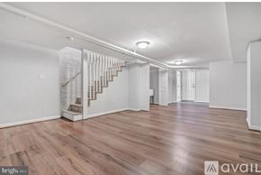 Washington house for rent - A spacious room with wooden flooring and a staircase with a glass railing.