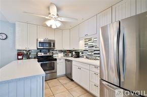 New Smyrna Beach townhouse for rent - A modern kitchen with a stainless steel refrigerator and white cabinets.