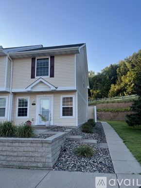 River Falls townhouse for rent - A house with a white door and windows is shown with a stone wall and plants in front.