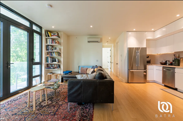 Brooklyn apartment for rent - A modern living room with a black sofa and a wooden floor.