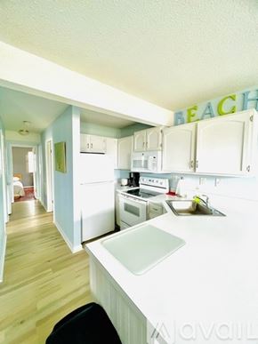 Ocean City apartment for rent - A kitchen with a white counter top and a sign that says "BEACH" on the wall.