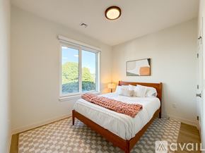 Boston apartment for rent - A bedroom with a large bed and a window overlooking a green landscape.